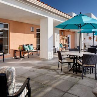 A sunny outdoor patio area with tables, chairs, and umbrellas.