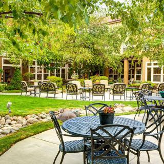 A peaceful garden patio with tables and chairs surrounded by lush greenery.