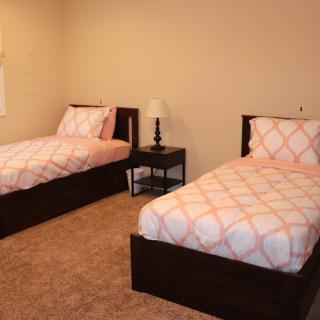 A simple bedroom with two twin beds and a nightstand.