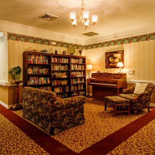 A cozy room featuring a bookshelf filled with books, a piano, and comfortable seating.