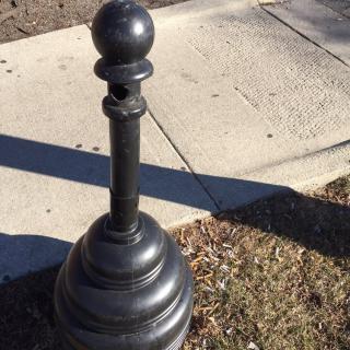 A decorative bollard on a city sidewalk.