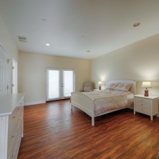 A spacious, minimalist bedroom with wood flooring and ample natural light.