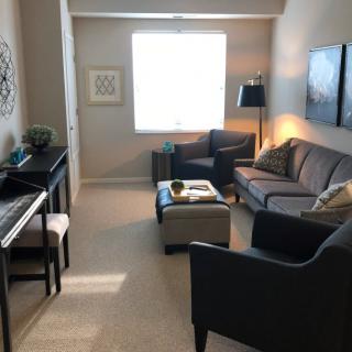 A cozy living room with a sofa, armchairs, a piano, and a coffee table.