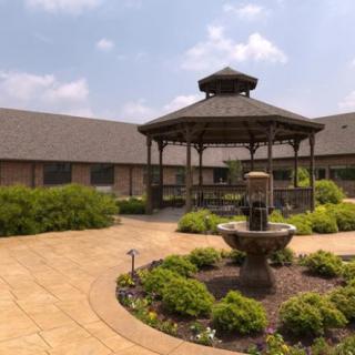A peaceful courtyard featuring a central gazebo surrounded by lush greenery and a decorative fountain.