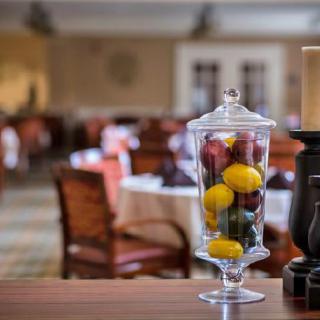 A cozy restaurant interior featuring a decorative apothecary jar filled with colorful fruits on the table.