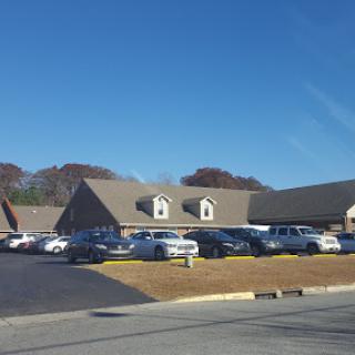 A view of a building surrounded by parked vehicles under a clear blue sky.