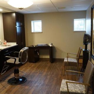 An empty salon room with a barber chair, mirrors, and additional seating.