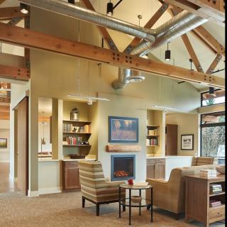 A modern living room with exposed wood beams, a fireplace, and comfortable seating.