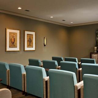 A small, empty theater room with rows of cushioned chairs and artwork on the walls.