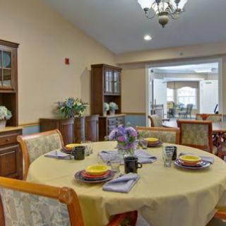 A well-decorated dining room with a round table set for a meal, featuring elegant chairs and a chandelier.