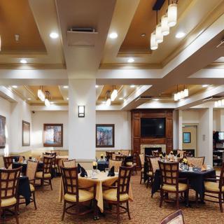 A cozy restaurant dining area featuring neatly arranged tables and chairs under warm lighting.