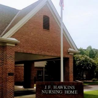The entrance to J.F. Hawkins Nursing Home, featuring a brick structure and a sign.