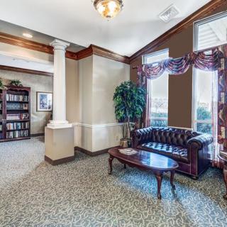 A cozy waiting room with a leather sofa, coffee table, and bookshelf.