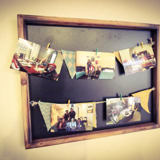 A rustic wooden frame showcasing a collection of photos clipped on strings.