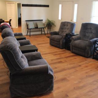 A cozy living room with multiple recliner chairs arranged on a wooden floor.