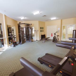 A spacious gym with various exercise equipment including treadmills and weights.