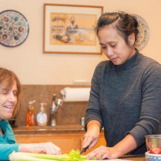 Two women sharing a joyful moment while preparing food together in the kitchen.