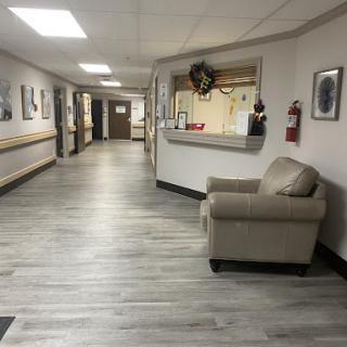 A well-lit hallway featuring a comfortable chair and decorated walls.