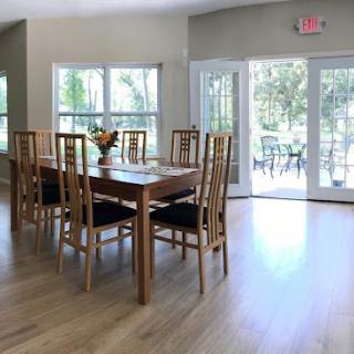 A bright and spacious dining area featuring a wooden table surrounded by chairs, illuminated by natural light.
