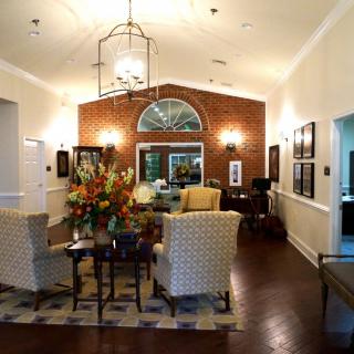 A cozy living room with elegant furniture, a brick accent wall, and a chandelier.