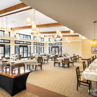 An elegant and spacious dining area with neatly arranged tables and chairs, well-lit by natural light from large windows.