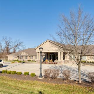 A residential building with a driveway and landscaped surroundings under a clear blue sky.