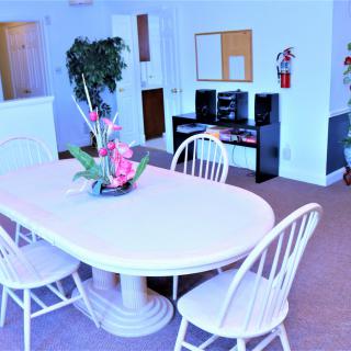 A bright dining room with a white table and chairs, decorated with a centerpiece and an indoor plant.