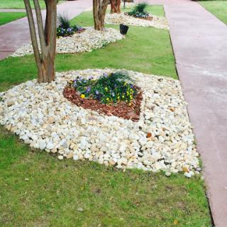 A beautifully landscaped garden featuring heart-shaped flower beds surrounded by decorative stones.