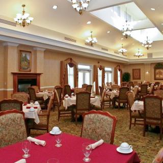 An elegant dining room with neatly arranged tables and chairs, illuminated by chandeliers.