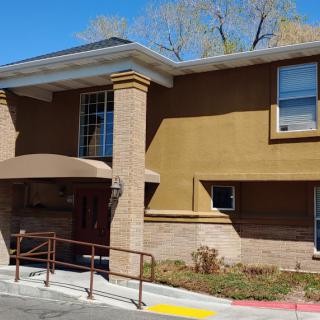 A building with an entrance ramp and large windows under a clear blue sky.