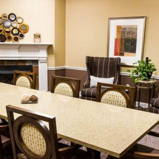 A well-decorated conference room featuring a large meeting table, comfortable chairs, wall art, and a cozy fireplace.