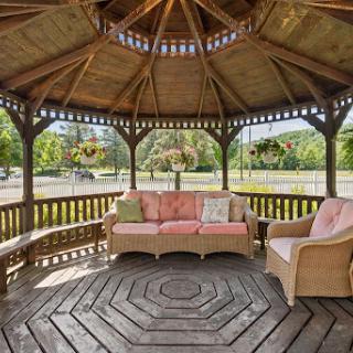 A cozy wooden gazebo featuring comfortable seating, perfect for enjoying the outdoors.