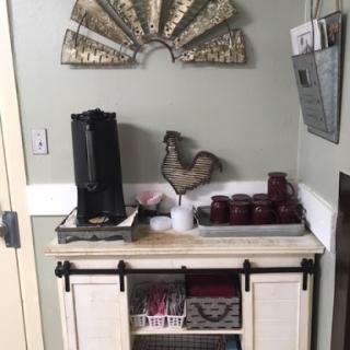 A cozy coffee station with country-themed decor, featuring a coffee maker, decorative chicken, and stylish storage.