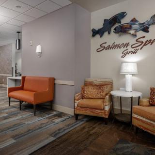 A cozy seating area in a lobby with comfortable chairs, couches, and decorative wall art.