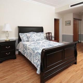 A cozy bedroom with a dark wooden bedframe and matching nightstand, featuring a lamp and patterned bedding.