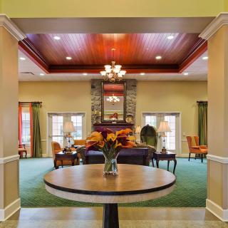 Elegant lobby with a centerpiece table, chandelier, and a cozy seating area near the fireplace.