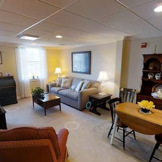 A cozy living room featuring a sofa, coffee table, and a dining area with warm lighting.