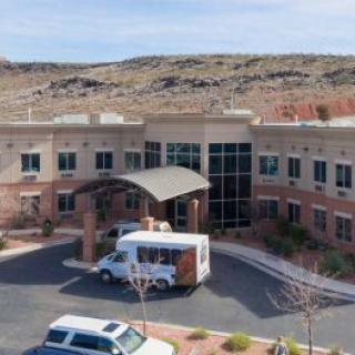 A hospital building with a parking lot and surrounding landscape.
