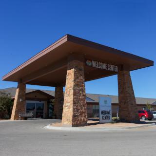 A roadside motel with a stone entrance and parking area under a clear blue sky.