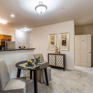 A modern dining area with a small table set, contemporary decor, and adjacent kitchen space.
