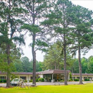 A scenic view of a motel surrounded by tall trees and greenery.