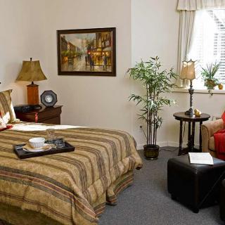 A cozy bedroom with a neatly made bed, decorative plants, and stylish furnishings.