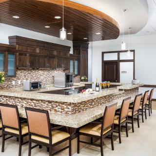 A modern kitchen with an elegant island counter and seating, featuring wooden cabinetry and stylish pendant lighting.