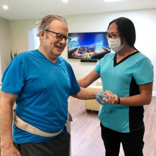 A caregiver assists a patient during a physical therapy session.