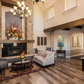 A modern living room featuring a cozy fireplace, elegant chandelier, and stylish furniture with wood flooring.