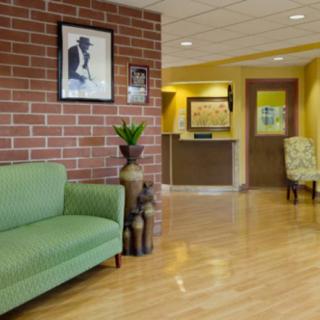 A cozy lobby with a green sofa, brick wall with artwork, and a reception desk.