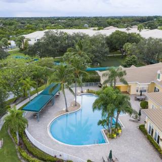 Aerial view of a residential area featuring a swimming pool surrounded by palm trees.