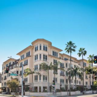 A residential apartment building surrounded by palm trees on a sunny day.