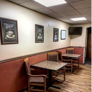 Interior of a cozy coffee shop with tables, chairs, and artwork on the walls.