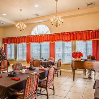 A spacious dining room with elegantly set tables, a grand piano, and festive Christmas decorations.